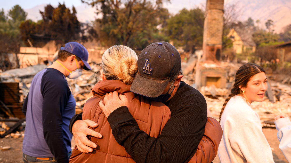 Family members hug and cry while viewing the burned remains of his home during the Eaton fire in the Altadena area of Los Angeles county, California on January 9, 2025