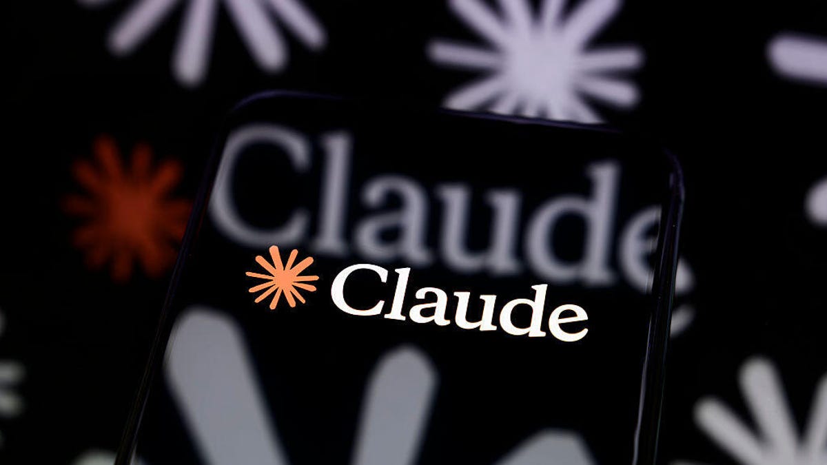 The Claude logo is displayed on a smartphone screen placed on a reflective surface onto which a multitude of Claude logos are projected