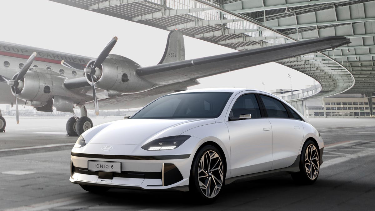 White Hyundai Ioniq 6 electric sedan next to an airplane
