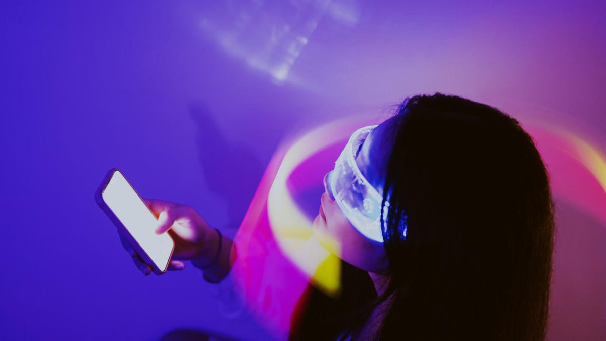 Person wearing virtual-reality goggles is holding a smartphone.