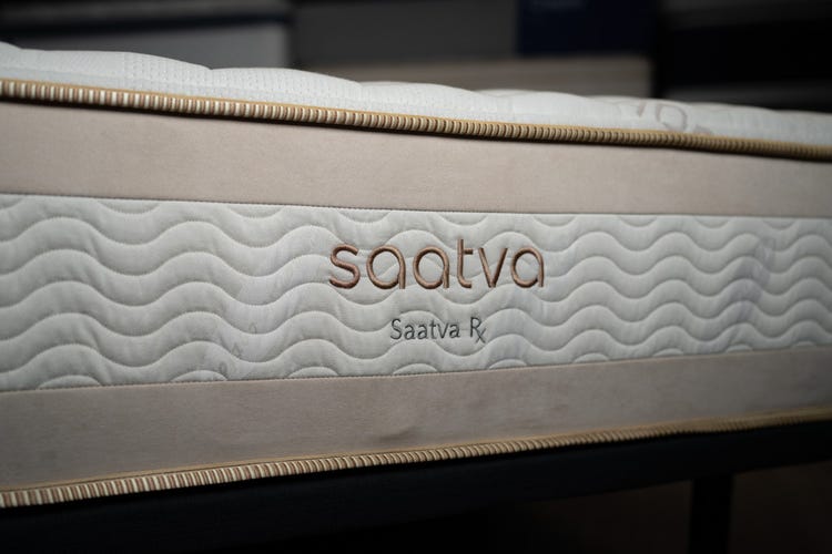 The edge of a white and tan Saatva mattress