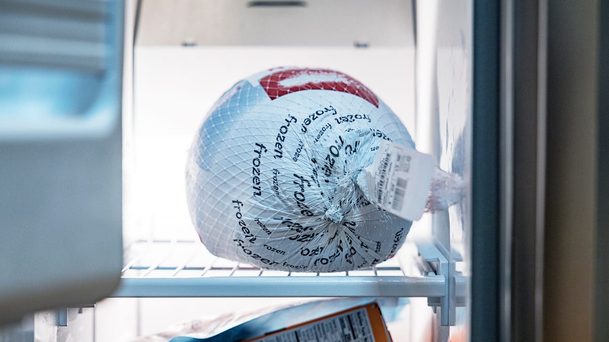 A wrapped turkey is on a shelf in the freezer.