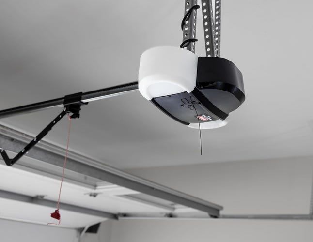 A Genie garage door motor hangs from a gray garage ceiling.
