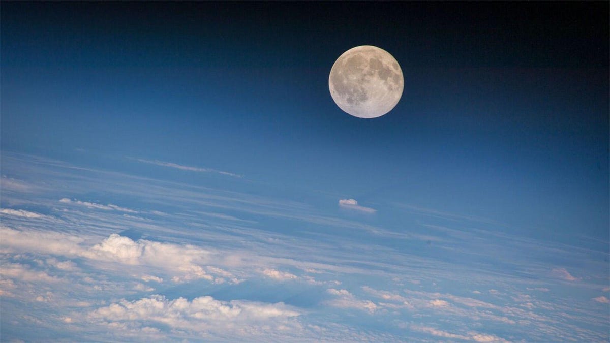 A full moon from a view above the clouds.