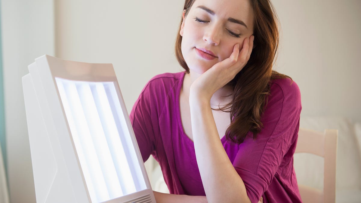 Woman using light therapy with a sun lamp to manage seasonal affective disorder