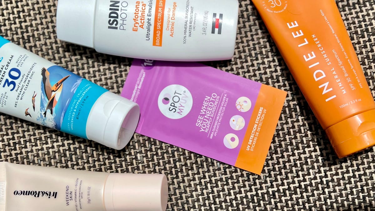 SpotMyUV stickers on a pool chair surrounded by five mineral sunscreens.