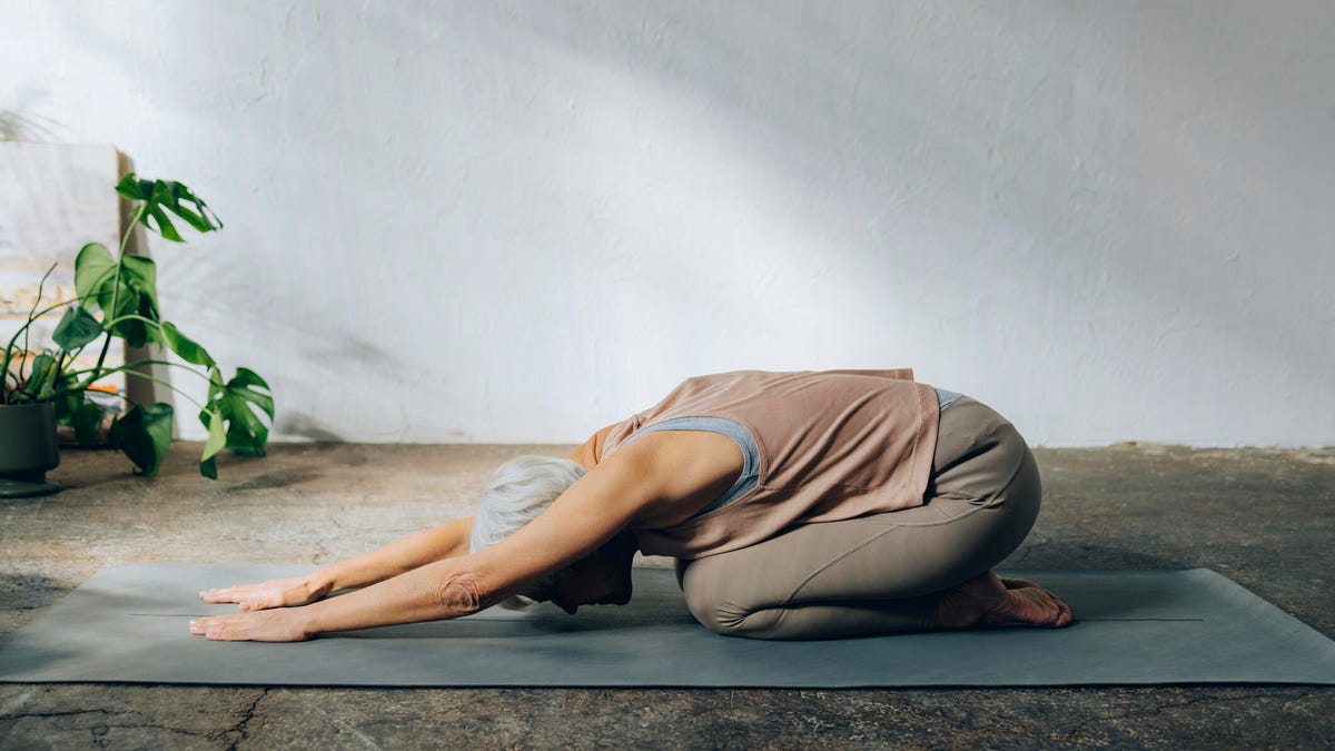 Woman lying on bed doing yoga against the wall