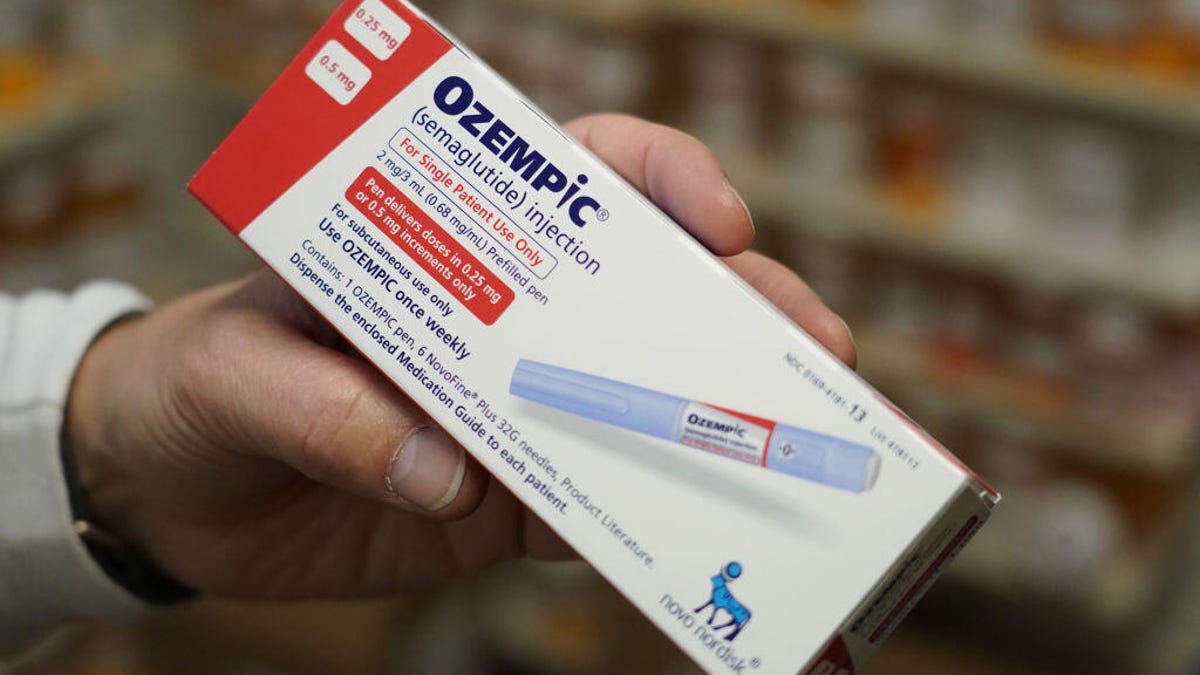 A pharmacist's hand holding a box of Ozempic