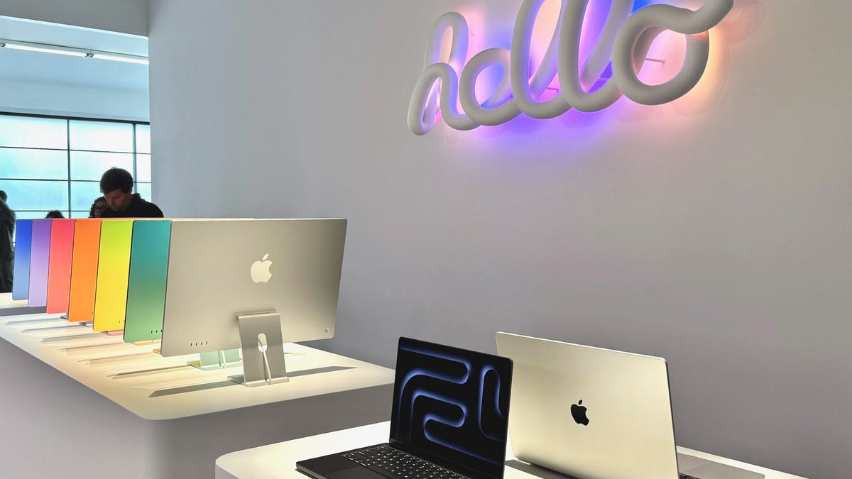 A row of colorful iMacs and a MacBook Pro under a Hello sign