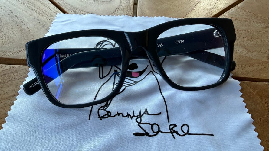 The black James reading glasses from Benny's on a glasses cleaning cloth.