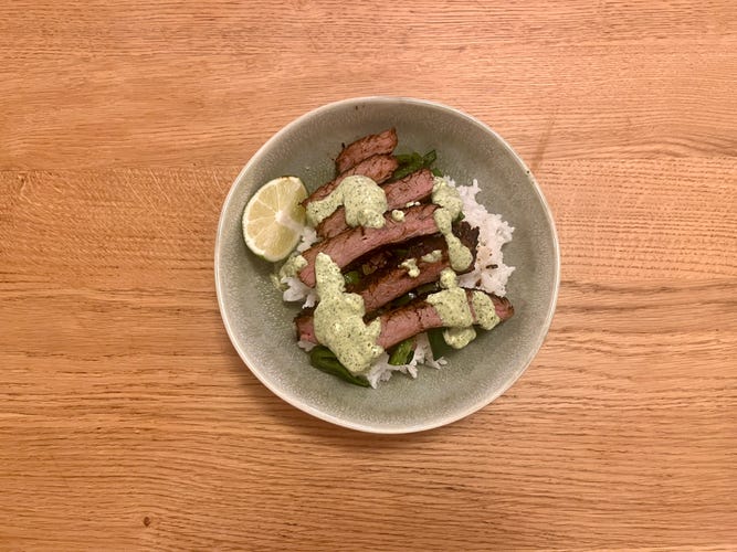 a bowl with steak and rice sitting on a countertop