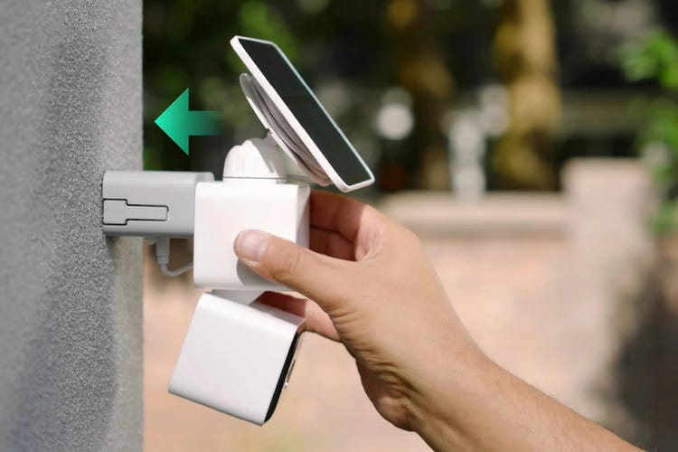 A hand mounts the Wyze cam and solar panel on a stucco wall.