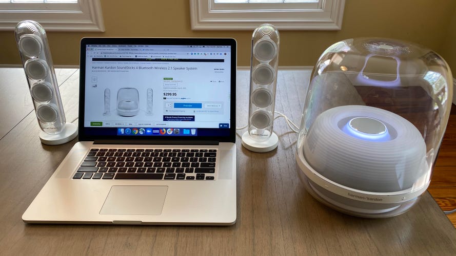 A laptop is flanked by Harman Kardon Soundsticks 4 speakers for PC.