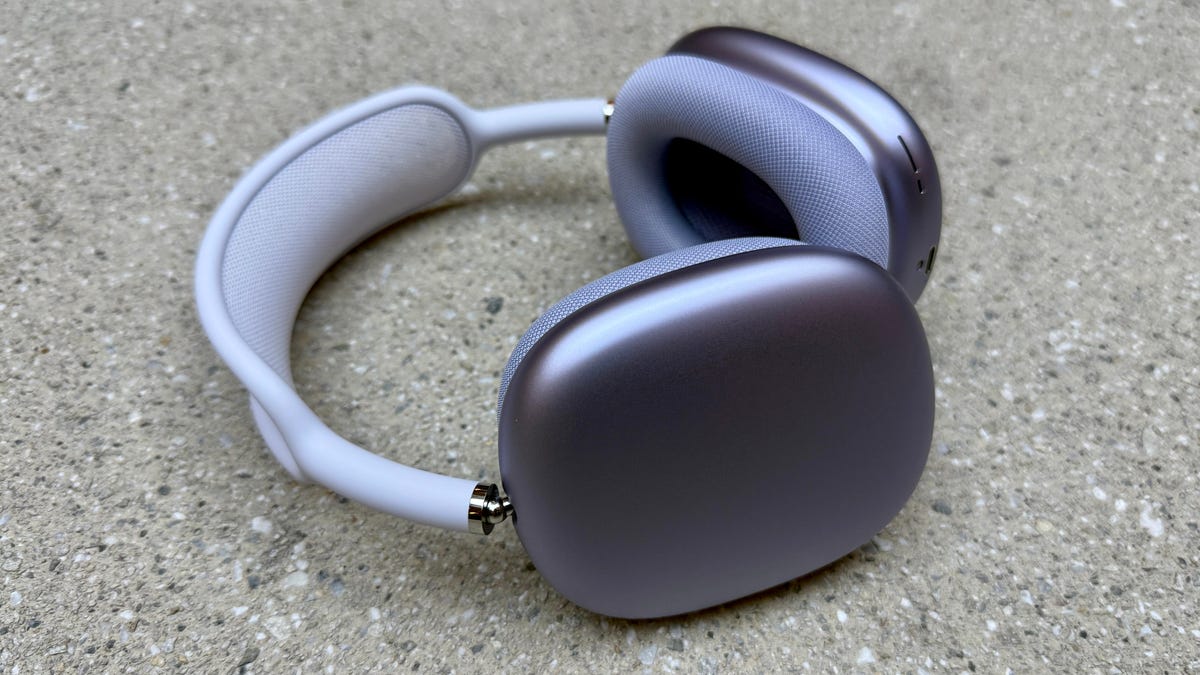 The purple version of the AirPods Max 2 laying on their side on a slate surface