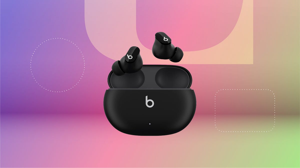 A pair of black Beats Studio Buds against a purple, pink and green CNET gradient background.