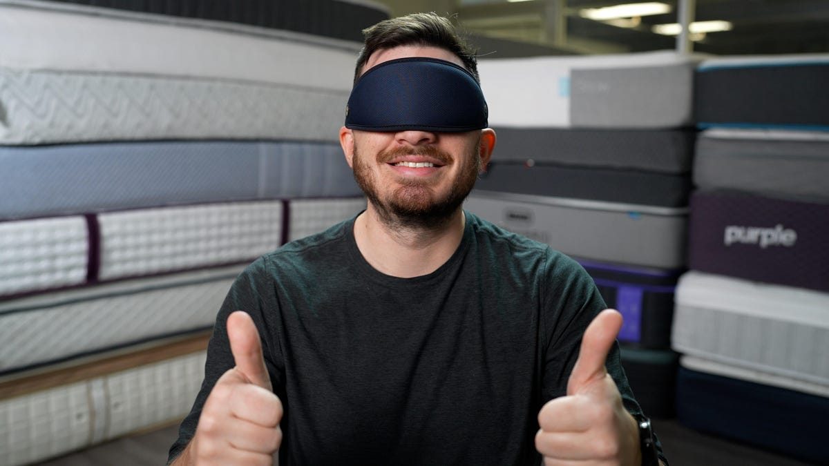 Owen, our mattress expert, in front of a pile of mattresses.