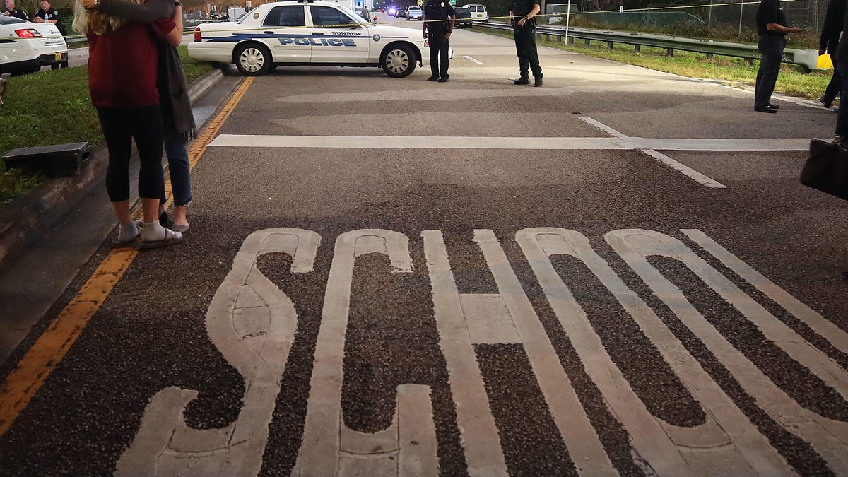 Two women hug at a police checkpoint near Marjory Stoneman Douglas High School, where 17 people were killed by a gunman Wednesday.