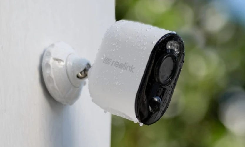 A Reolink Argu cam mounted to a white outdoor well with fresh rain.