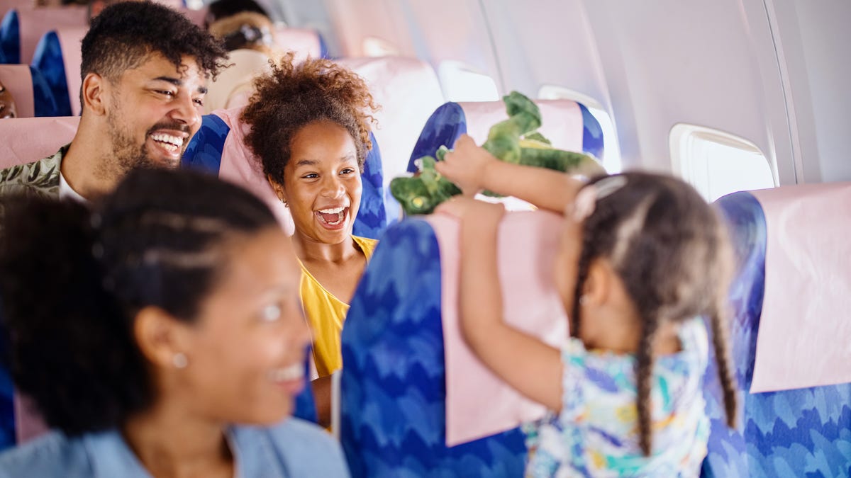 Two young girls play with stuffed animals on a plane.