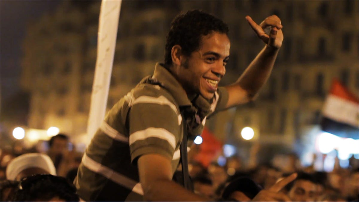 A young activist held aloft by Egyptians protesting