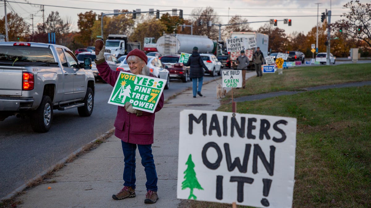 Marcia Taylor of Cape Elizabeth holds a "Vote Yes on 3" sign during morning rush hour traffic in South Portland, Maine, on Nov. 1, 2023.