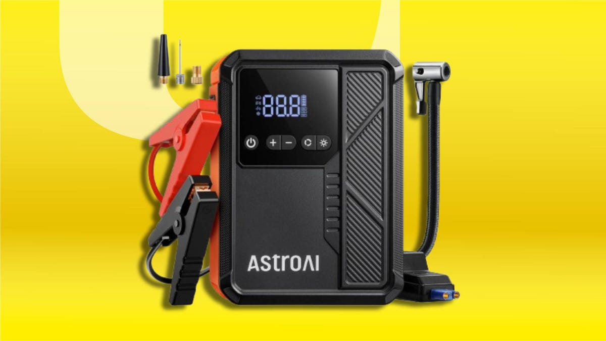 Black portable jump starter with built-in air compressor, digital display, jumper clamps, inflation hose and nozzle attachments on CNET background