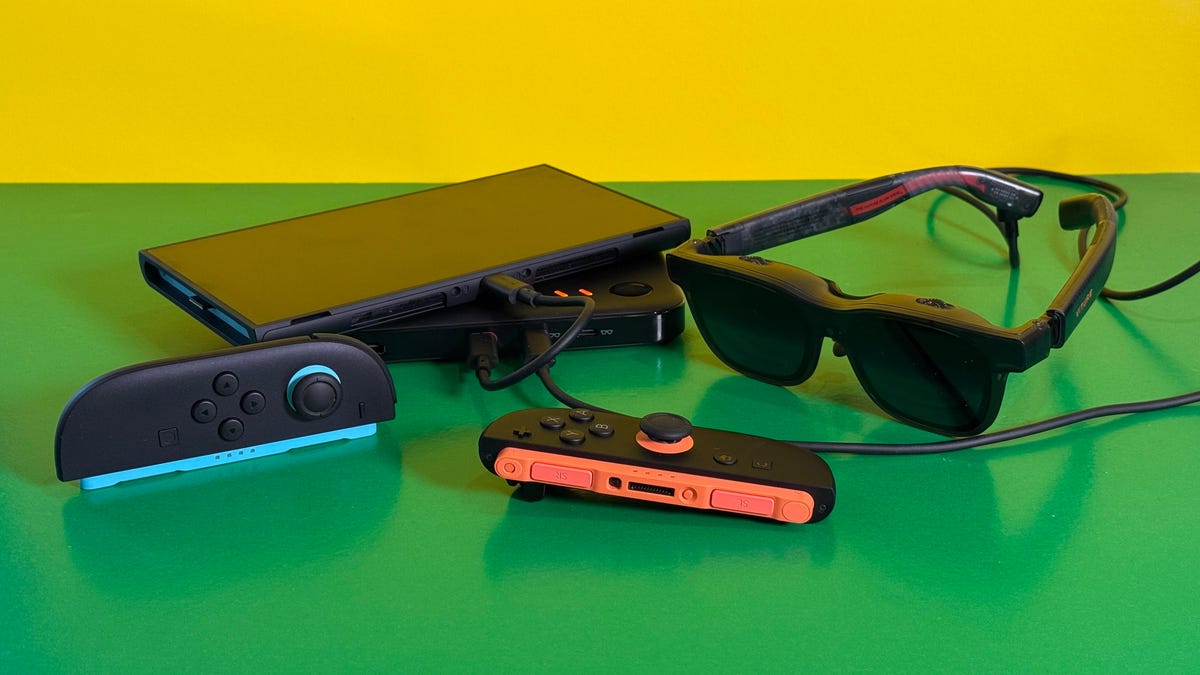 A pair of smart glasses made by Viture called Luma Pro plugged into a Nintendo Switch 2 using a battery pack dock