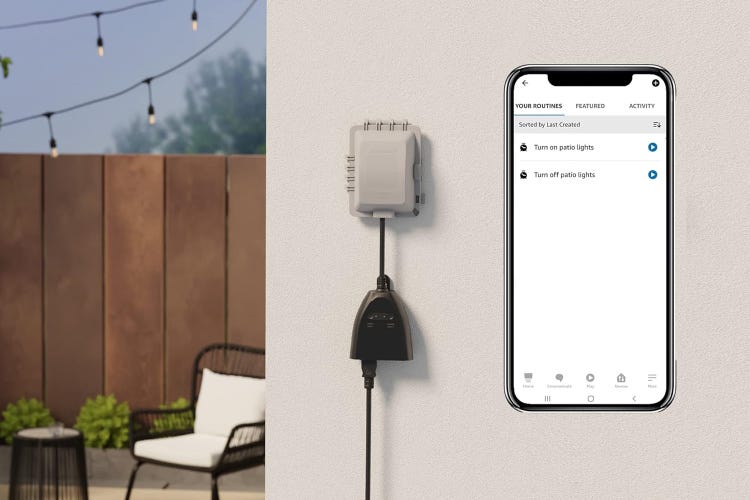 An Amazon Basics outdoor smart plug on a gray wall next to a patio with the app shown beside it.