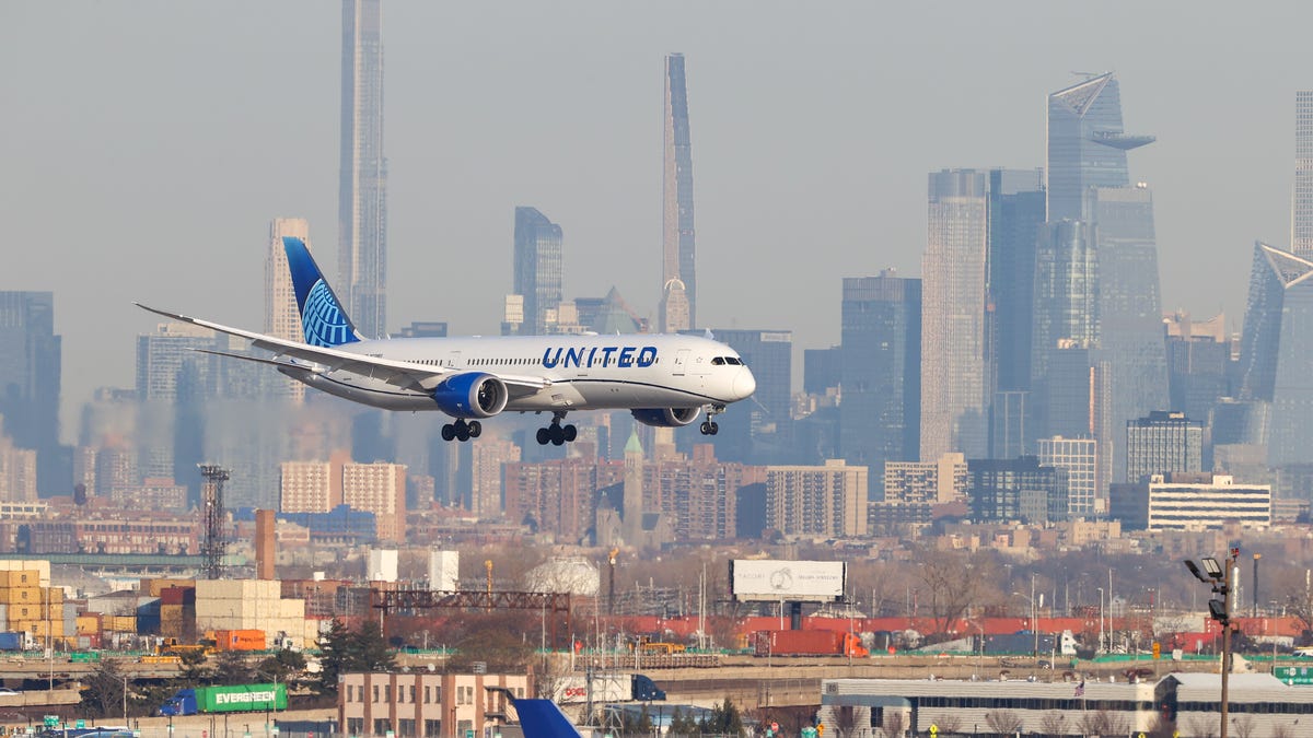 A United jet lands at Newark Liberty International Airport with the Manhattan skyline in the background.