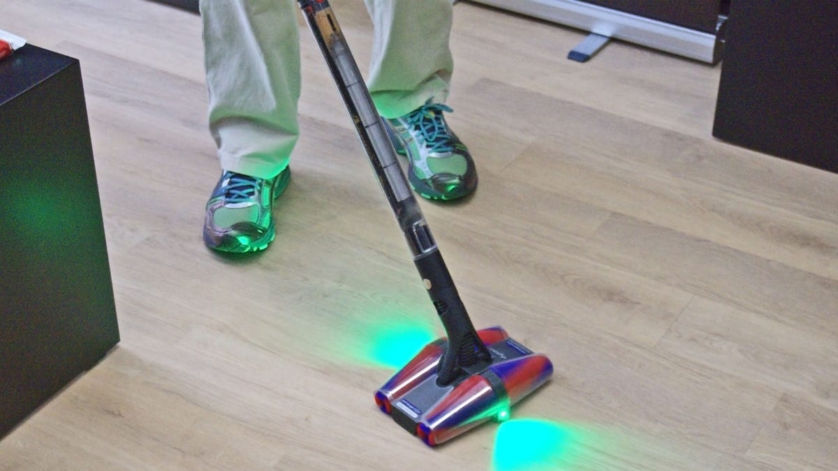A person is vacuuming hard flooring with the new Dyson PencilVac.