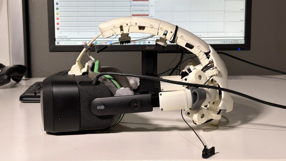 A prototype VR headset, called Galea, with a white plastic headband sitting on a desk