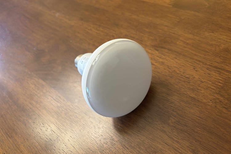 A Philips Hue floodlight bulb on a wood surface.