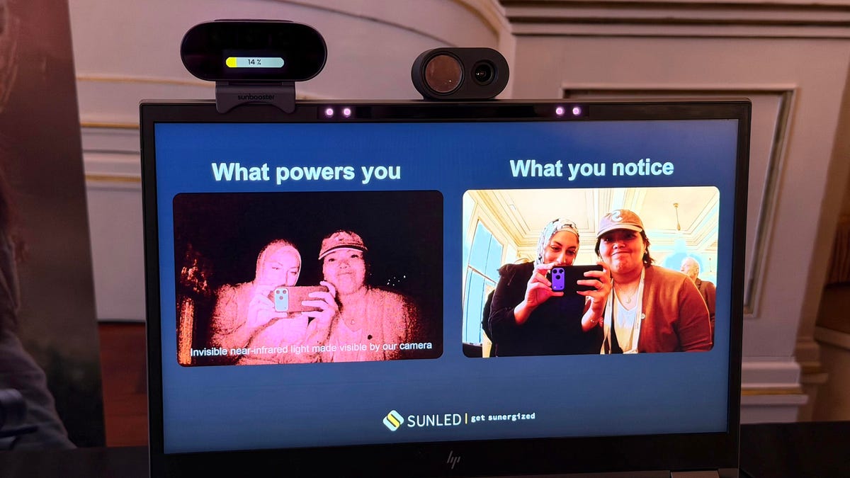 A laptop with the SunBooster mounted on top of the screen. Two people look into an adjacent webcam