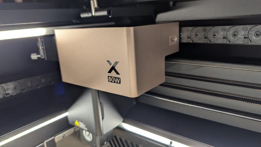 A close up of the laser module on the P3 laser cutter. It's nickel colored with an X and the words 80W