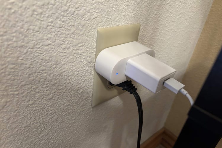 Emporia's smart plug in a wall outlet on a white wall.