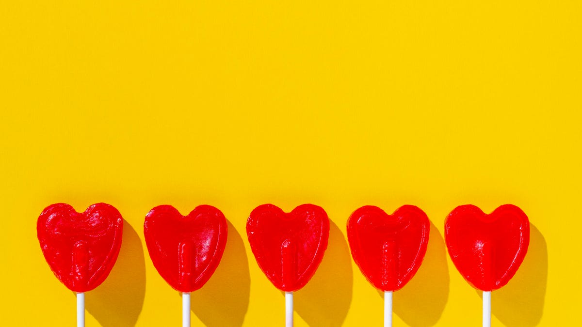five red, heart-shaped lollipops on a yellow background