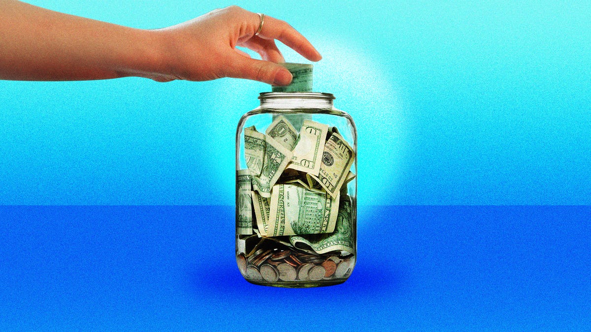 Hand adding cash to a tip jar