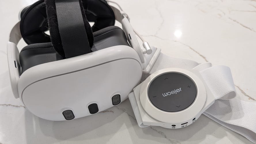 A Meta Quest 3 with the Woojer haptic Strap 3 next to it