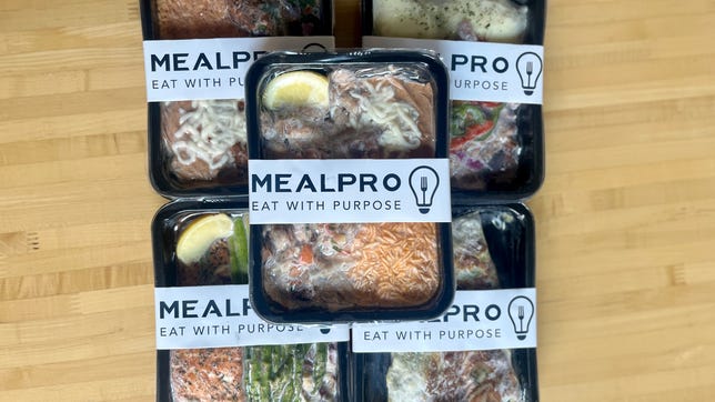 five premade meals on a wooden table