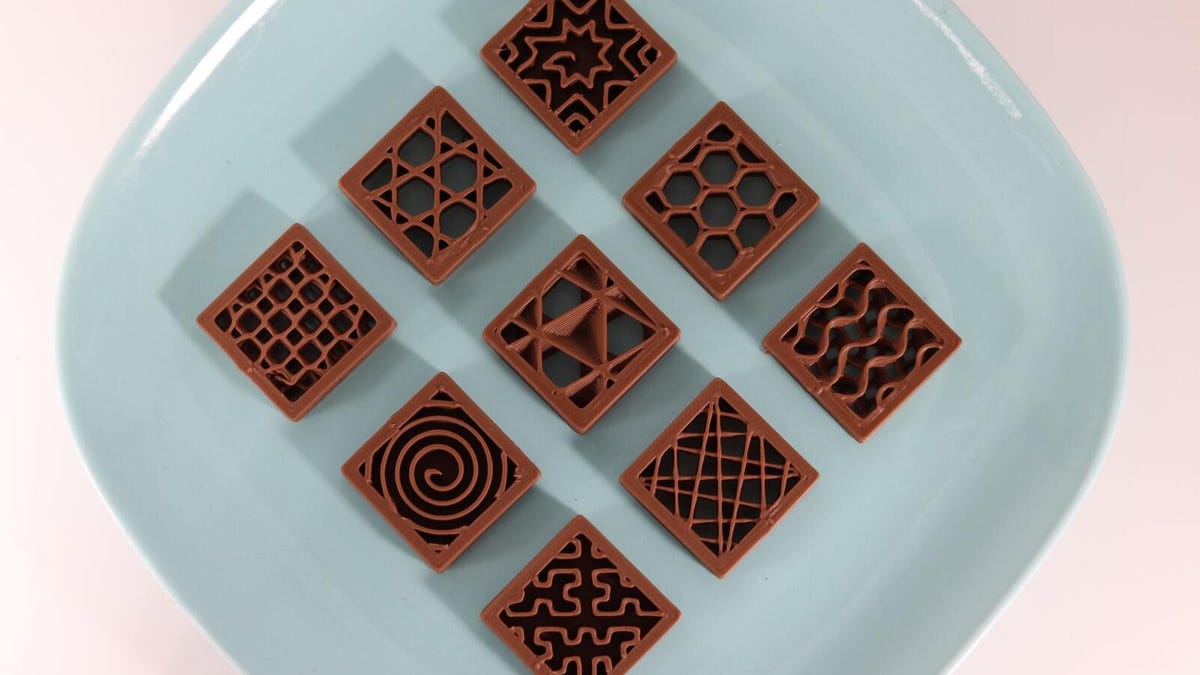 Blue plates with nine square fancy chocolates on it.