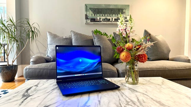 Alienware 16X Aurora laptop sitting on a coffee table next to a vase of flowers