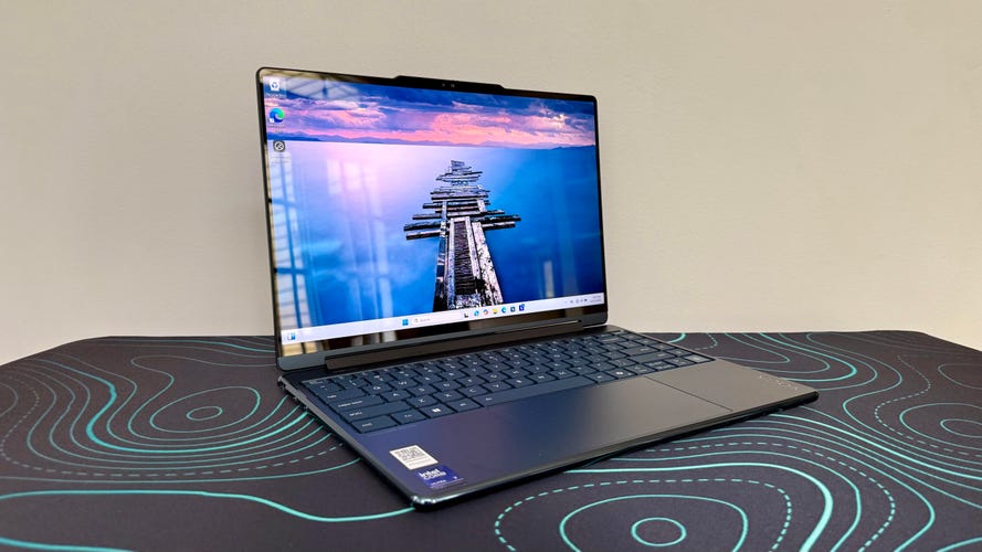 Lenovo Yoga 9i 2-in-1 Aura Edition laptop on a black desk pad with blue lines