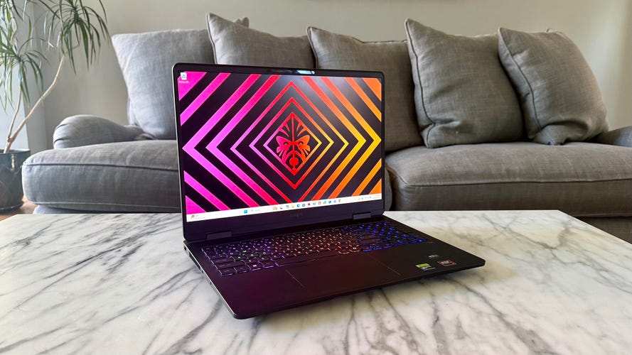 HP Omen 16 gaming laptop on a marble coffee table in front of a gray sofa