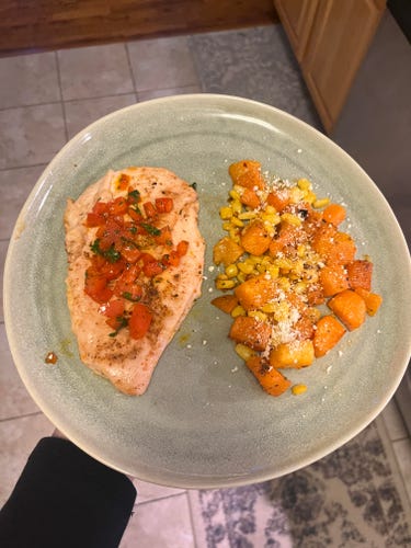 a person holding a green plate with chicken and veggies on it