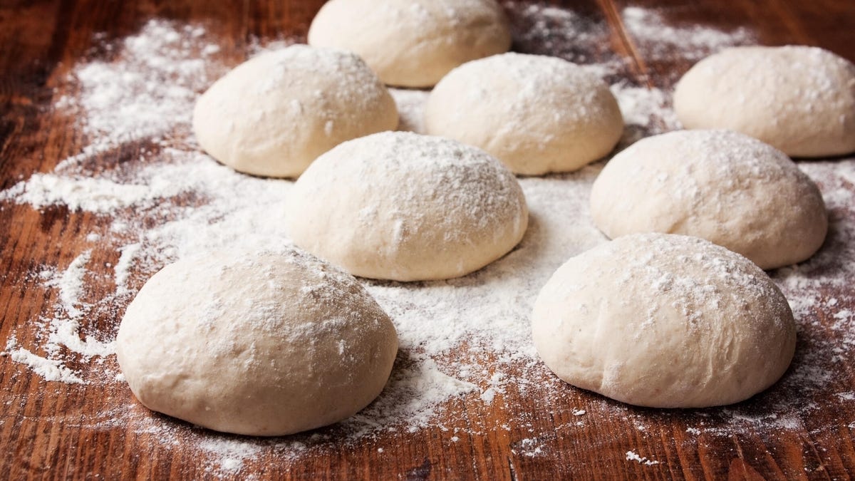 Pizza dough balls on a flour covered board