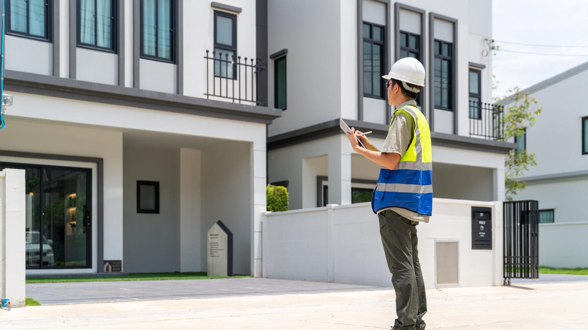 A person standing outside a home with a clipboard