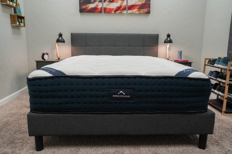 The DreamCloud Hybrid mattress on a gray bed frame with two nightstands next to it.