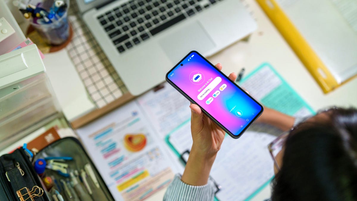 A student talks to a chatbot on the phone while working on school work.