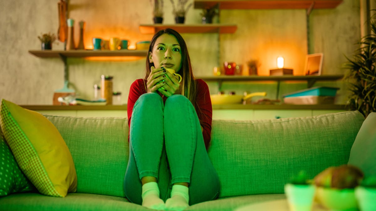 Woman sitting with her legs up on the couch, a mug in her hand.
