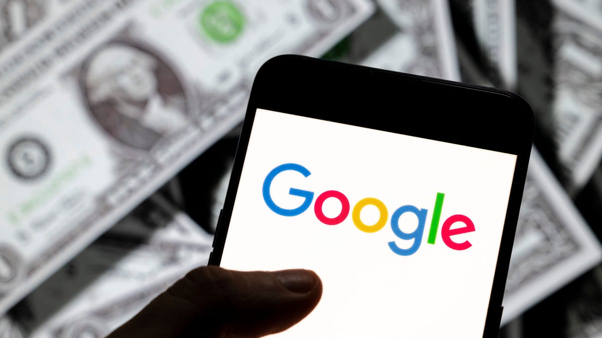 A phone with a Google logo with a background of several dollar bills.